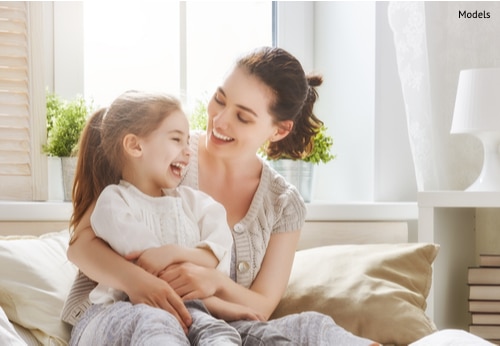 A mother holding her daughter while enjoying the results of her Mommy Makeover surgery.